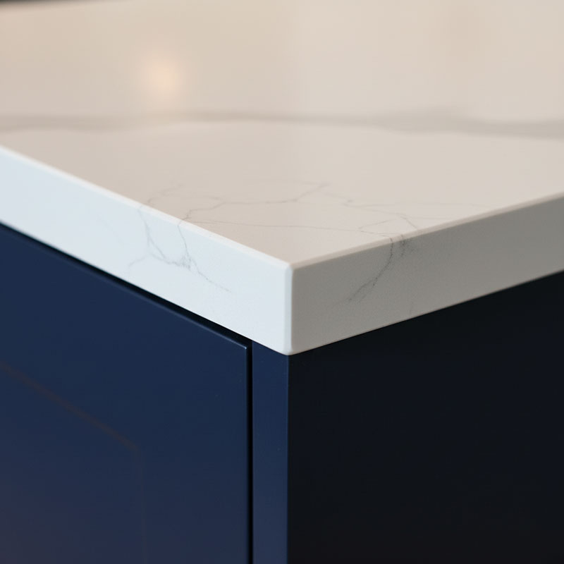 Close-up detail photograph of a 30mm quartz countertop square edge showing the full thickness profile against dark cabinetry