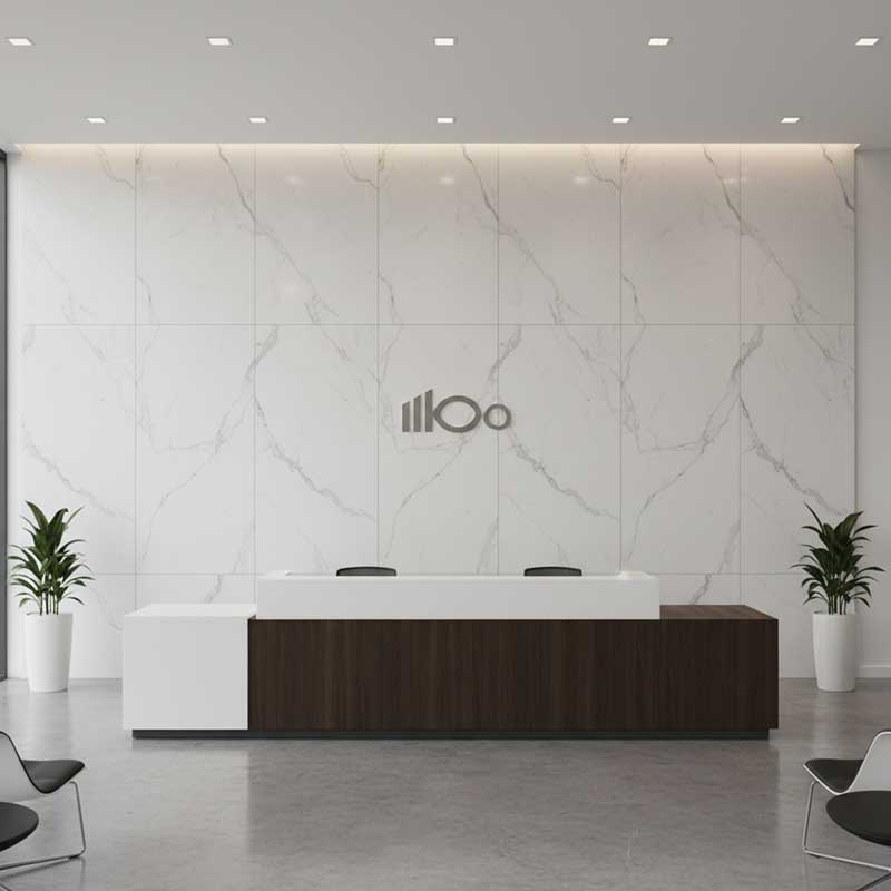 Modern corporate office reception area with large-format floor-to-ceiling white marble-look quartz wall panels behind sleek reception desk with company branding