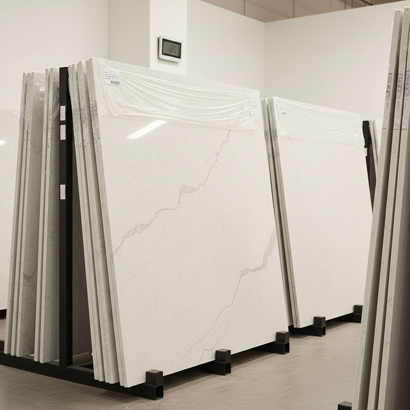 Engineered quartz stone slabs stored upright in an indoor temperature-controlled warehouse for 48-hour acclimatization before installation with visible thermometer showing room temperature